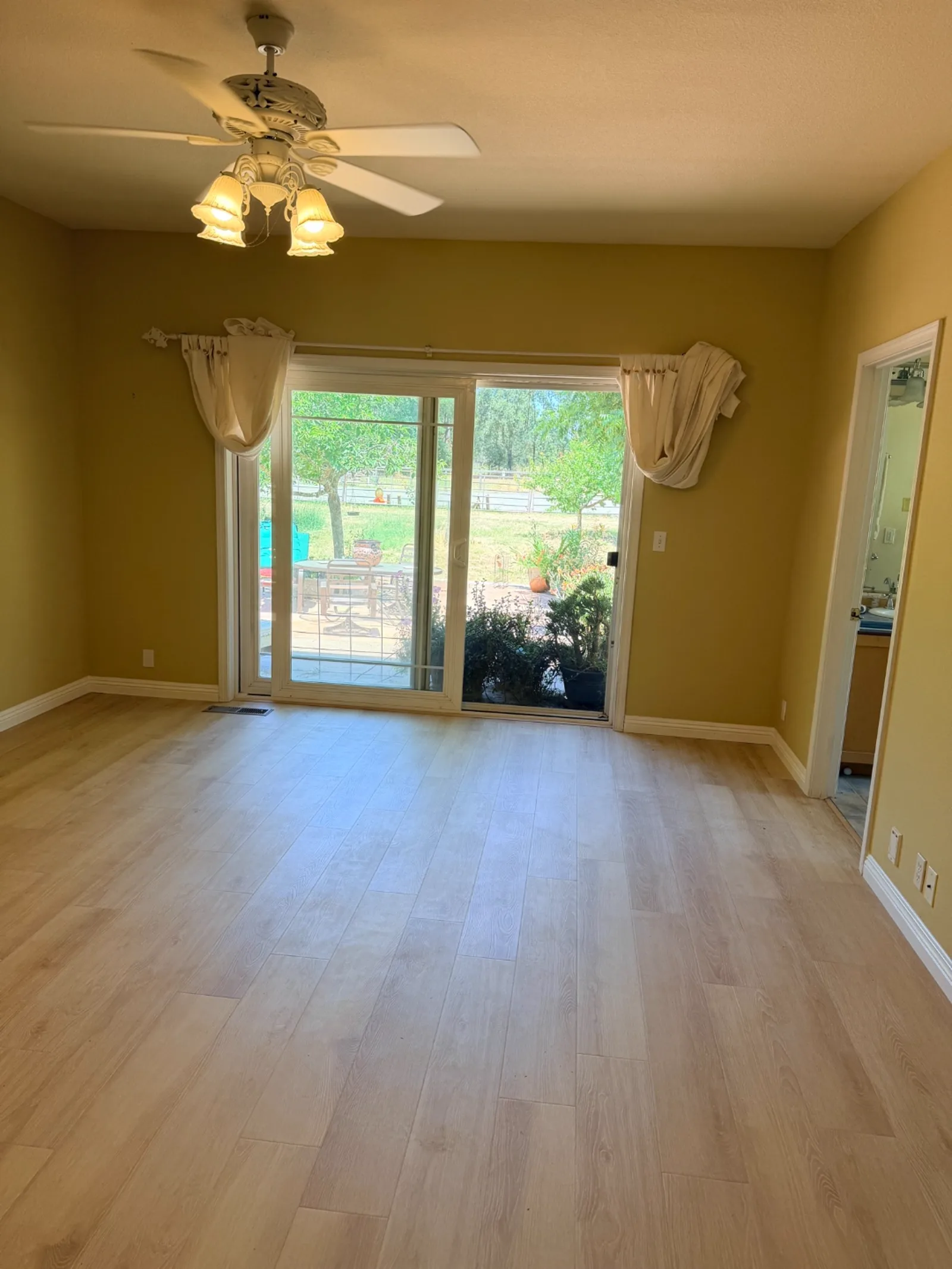 New light wood-look flooring installed in an open living room with sliding glass door