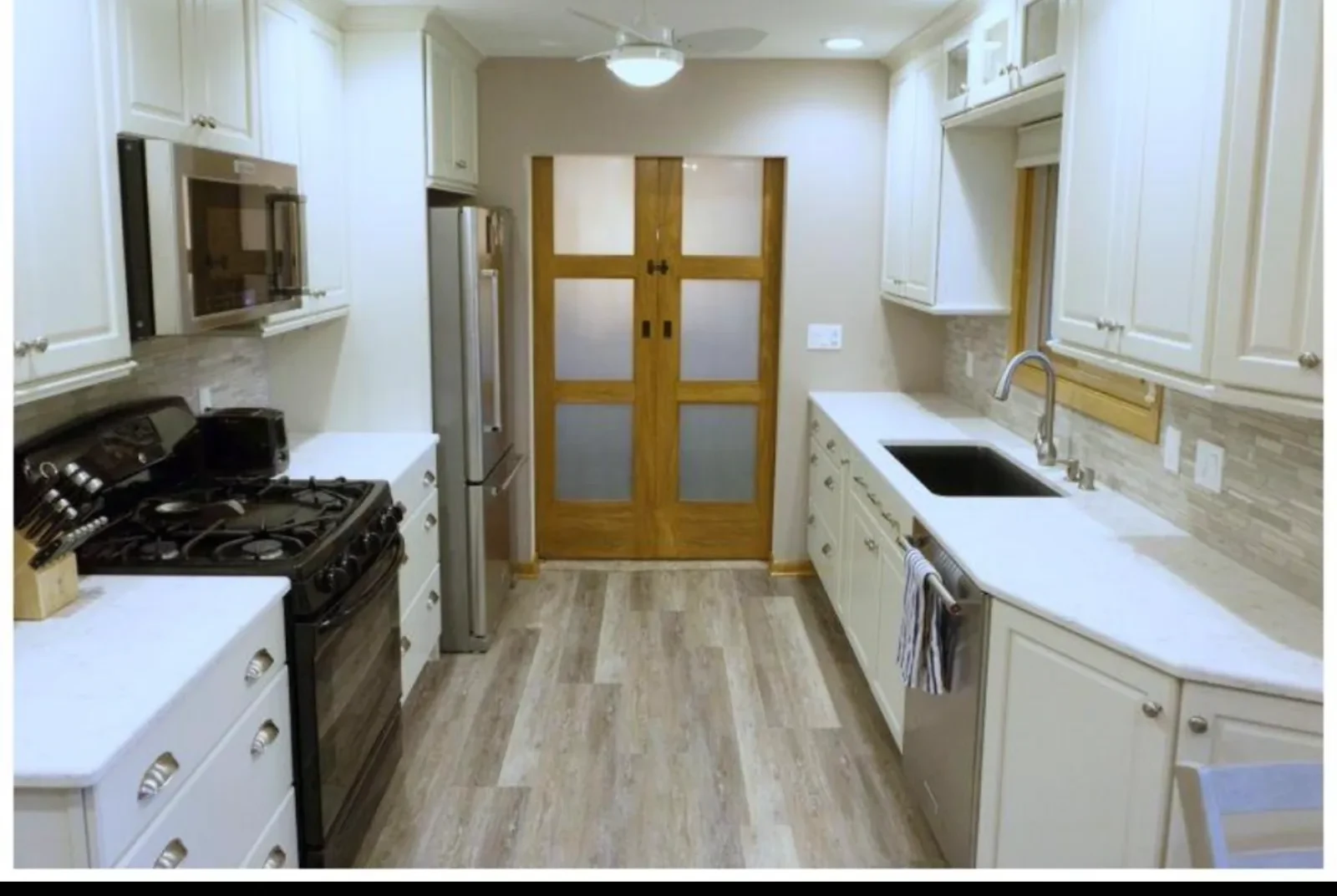 Kitchen after remodel: new white cabinets, stainless appliances, updated flooring