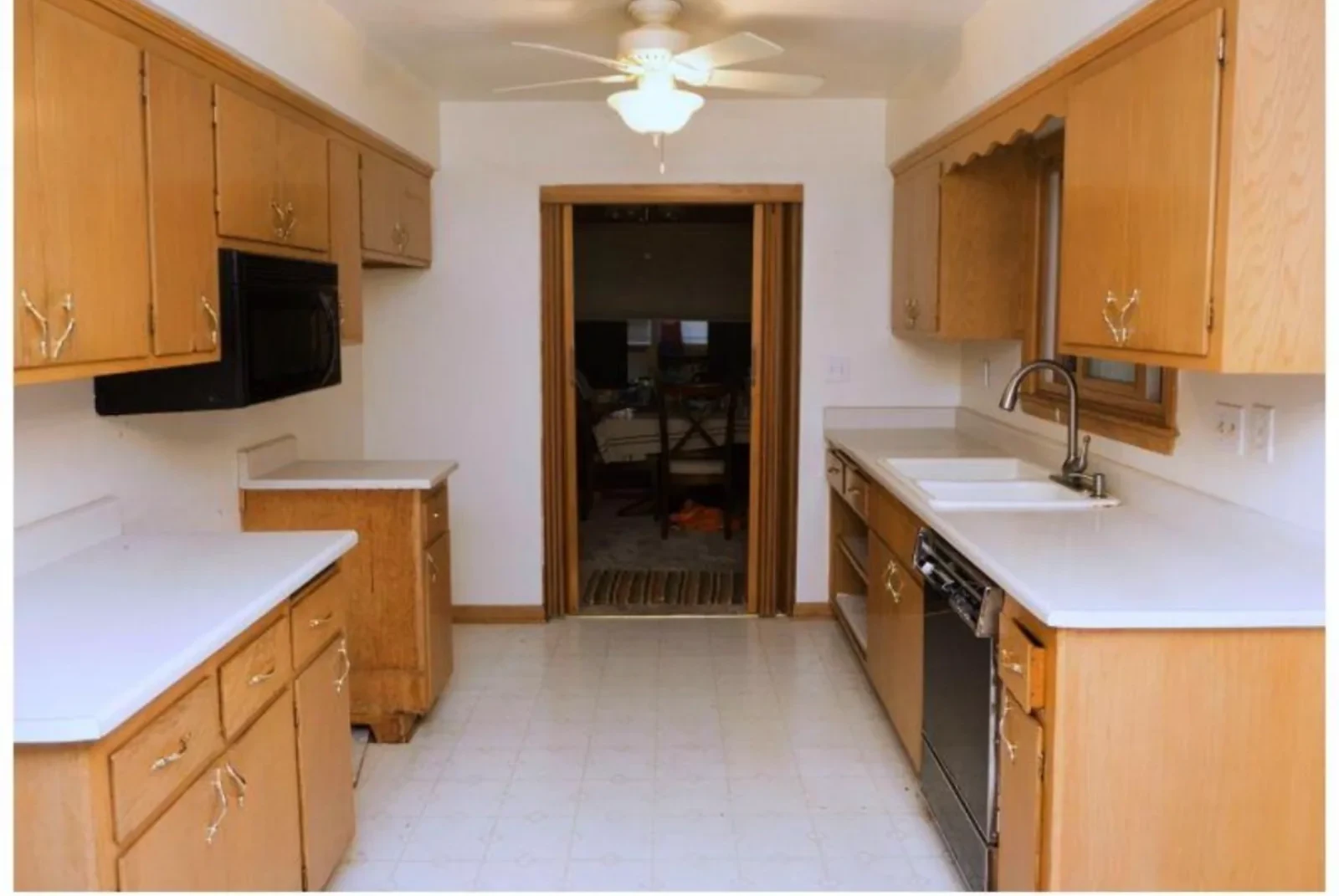 Kitchen before remodel: dated oak cabinets and worn tile floor